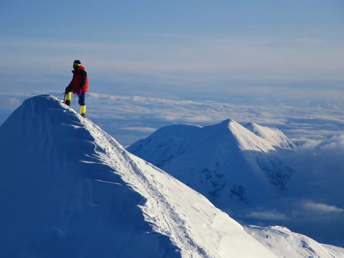 A mountain climber on the summit of a snowy peak