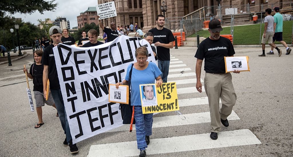 Anti-death penalty activists march with a sign to free Jeff Wood