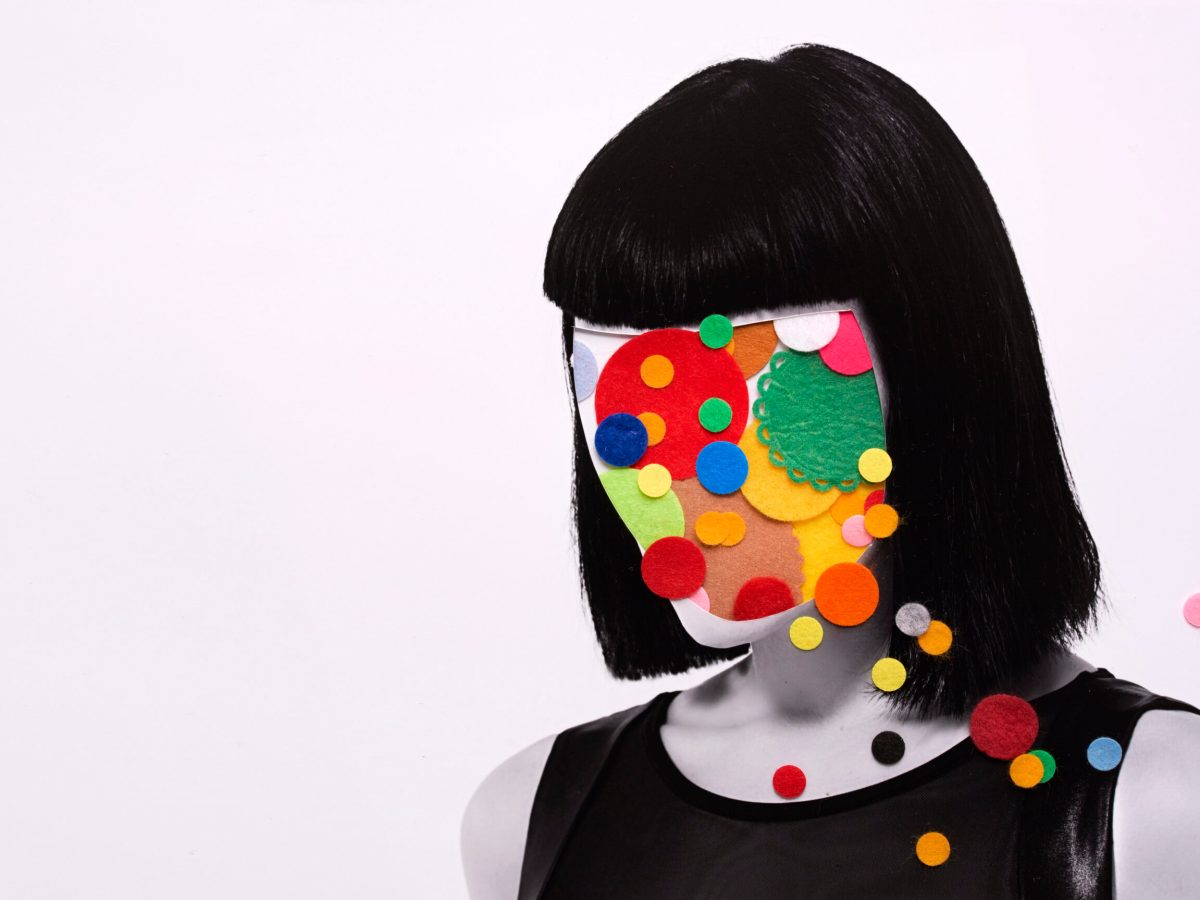 A woman with patches of colored felt obscuring her face