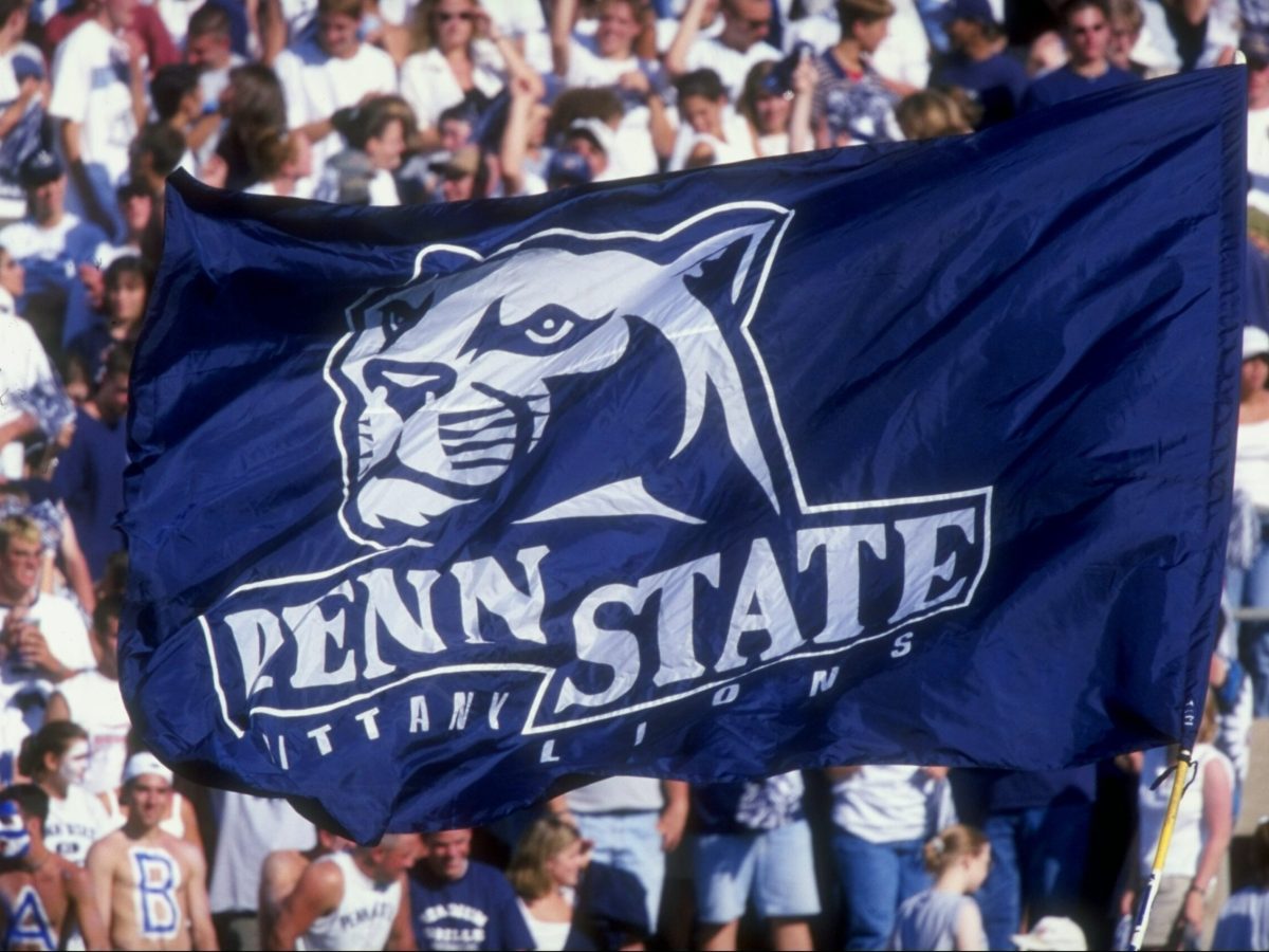 Penn State Nittany Lion fans hoist a flag up in the air during a game.