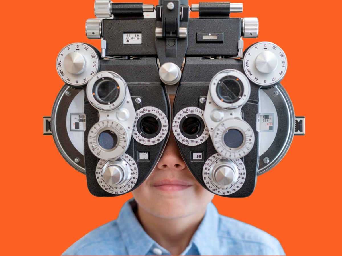 A child with his face obscured by a vision-testing machine