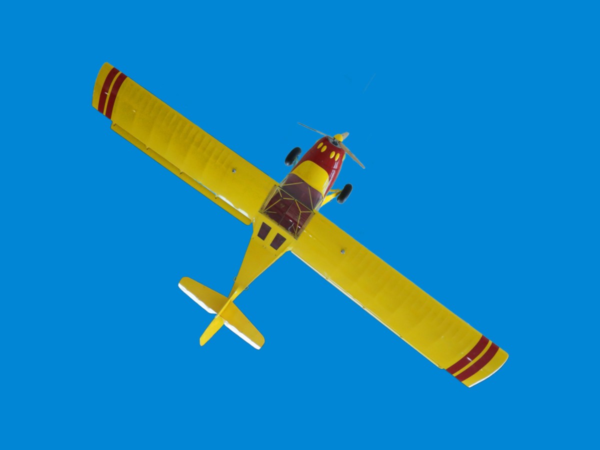 A bright yellow stunt plane on a sky-like blue background